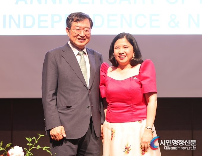  Ambassador Theresa Dizon De Vega of the Philippines clad in red upper-wear and pink skirts (right) poses with one of the Korean guests on the stage of the Regency Ballroom of the Grand Hyatt Seoul in celebration of the 125th anniversary of Independence of the Philippines from Spain.