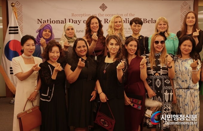Mrs. Chernetsky, the spouse of Amb. Andrew Chernetsky of Belarus in Seoul (fourth from left), presents a “love” sign with spouses of foreign ambassadors and Korean guests at a reception to mark the Independence Day of Belarus held at Lotte Hotel in Seoul on June 28.