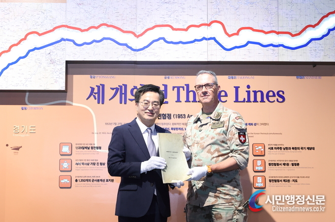 Governor Kim Dong-yeon of Gyeonggi Province (left) receives a copy of the Armistice Agreement from Ivo Burgener, the Swiss representative of the Neutral Nations Supervisory Commission at the "Armistice Agreement Handover Ceremony" held at Gallery Greaves within Paju Camp Greaves on July 19.