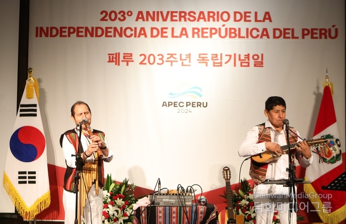 Two musicians are playing traditional Peruvian music for guests at a reception.