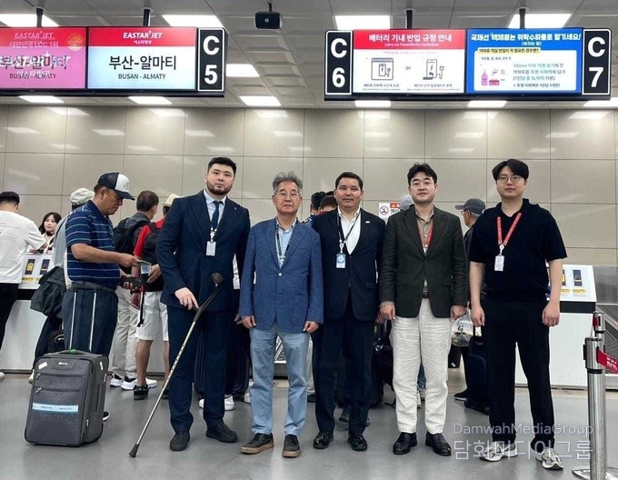 아슬란 아스카르 총영사, 이상훈 명예영사, 이스타항공 직원 및 카자흐스탄 총영사관 관계자들이 부산–알마티 노선 체크인 카운터 앞에 함께 서 있다.