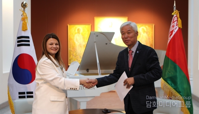 벨라루스 국립미술관장(좌측)과 외교저널 회장 이존영(우측)이 K-민화 작품 32점 기증 증서를 교환한 뒤 악수하고 있다.