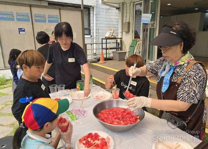 '우리마을 은빛 놀이터’프로그램에 참여한 어르신이 아이들에게 수박화채를 나눠주고 있다.