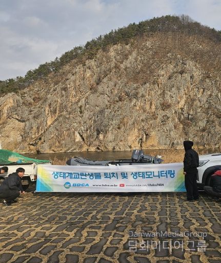 금산군 생태계 교란어종 퇴치 사업 관계자들이 활동에 나서며 현수막을 설치하고 있다.